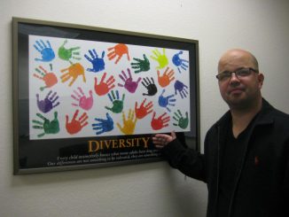 Mark Chartier in front of a poster with the word Diversity.